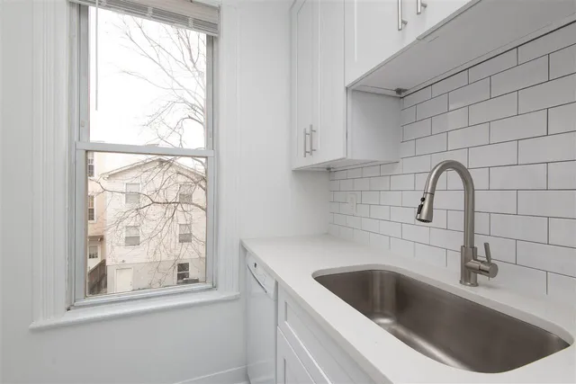 a view of a sink a window and cabinets
