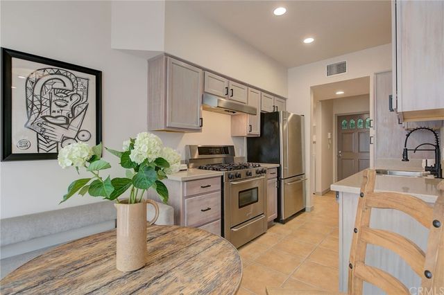 a kitchen with stainless steel appliances a stove a sink cabinets and a wooden floor