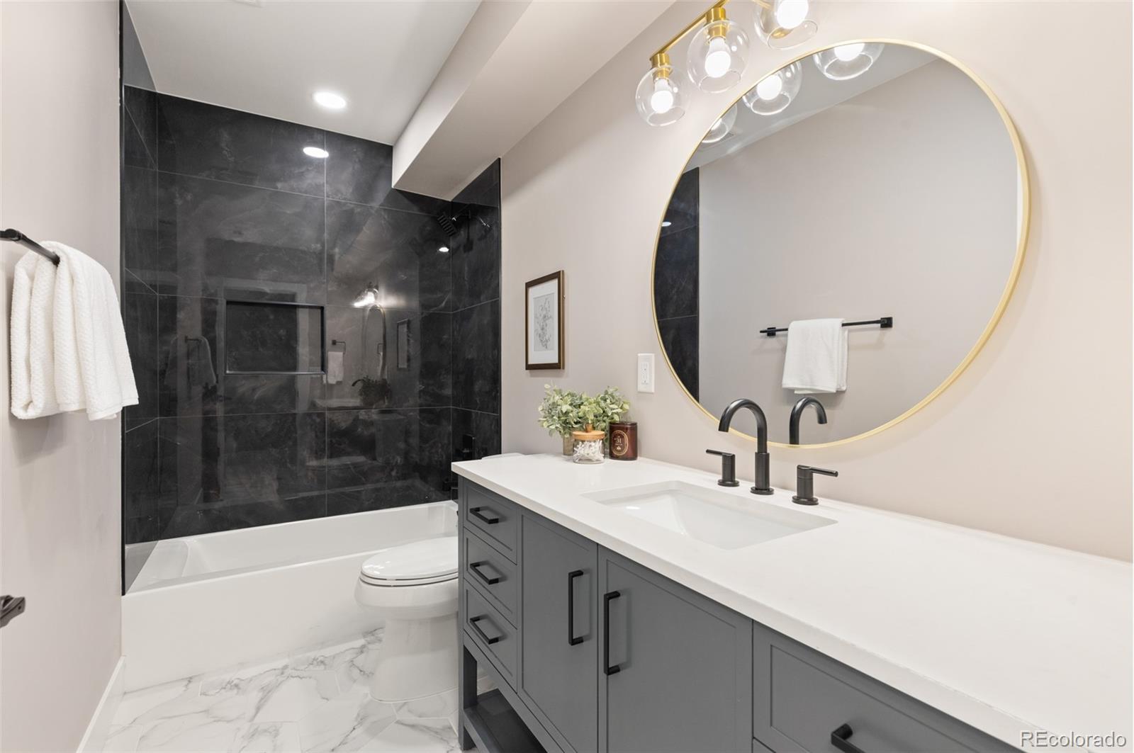 11895 West 35th Avenue Wheat Ridge, CO 80033 - Photo 43 of 50 a bathroom with a sink a toilet a mirror a bathtub and shower