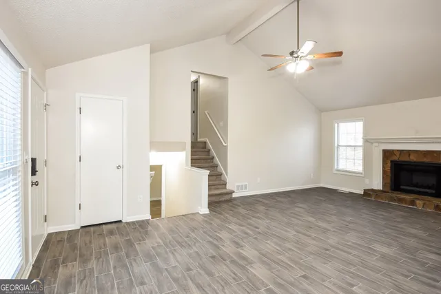 an empty room with wooden floor fan and windows