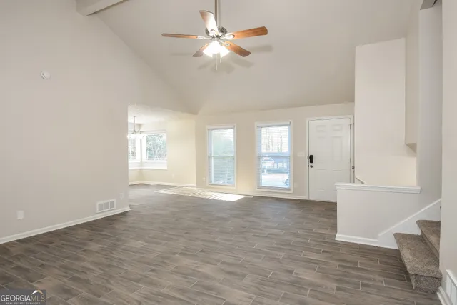 a view of an empty room with chandelier fan and a window