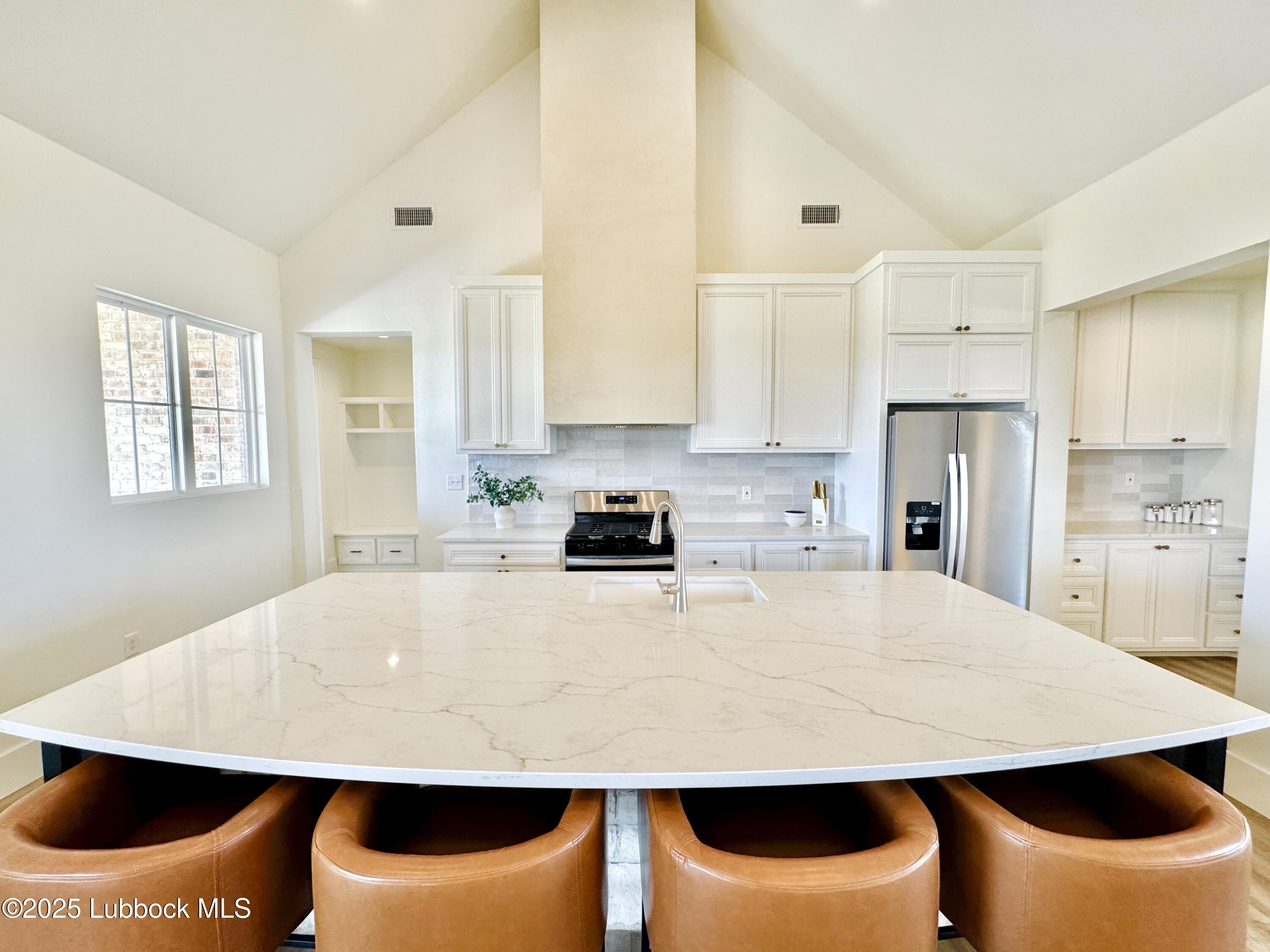 7211 West 12th Street Plainview, TX 79072 - Photo 15 of 48 a large white kitchen with kitchen island white cabinets and stainless steel appliances
