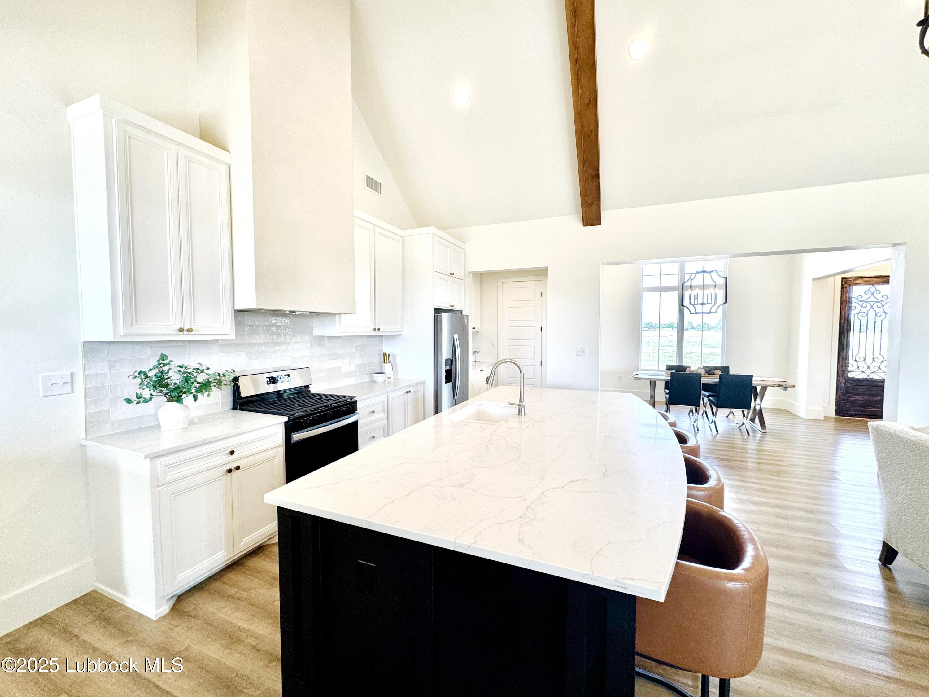 7211 West 12th Street Plainview, TX 79072 - Photo 16 of 48 a kitchen with stainless steel appliances kitchen island granite countertop a sink dishwasher and white cabinets with wooden floor