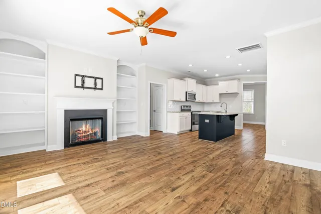 a large kitchen with stainless steel appliances granite countertop a stove top oven a sink and a fireplace with wooden floor