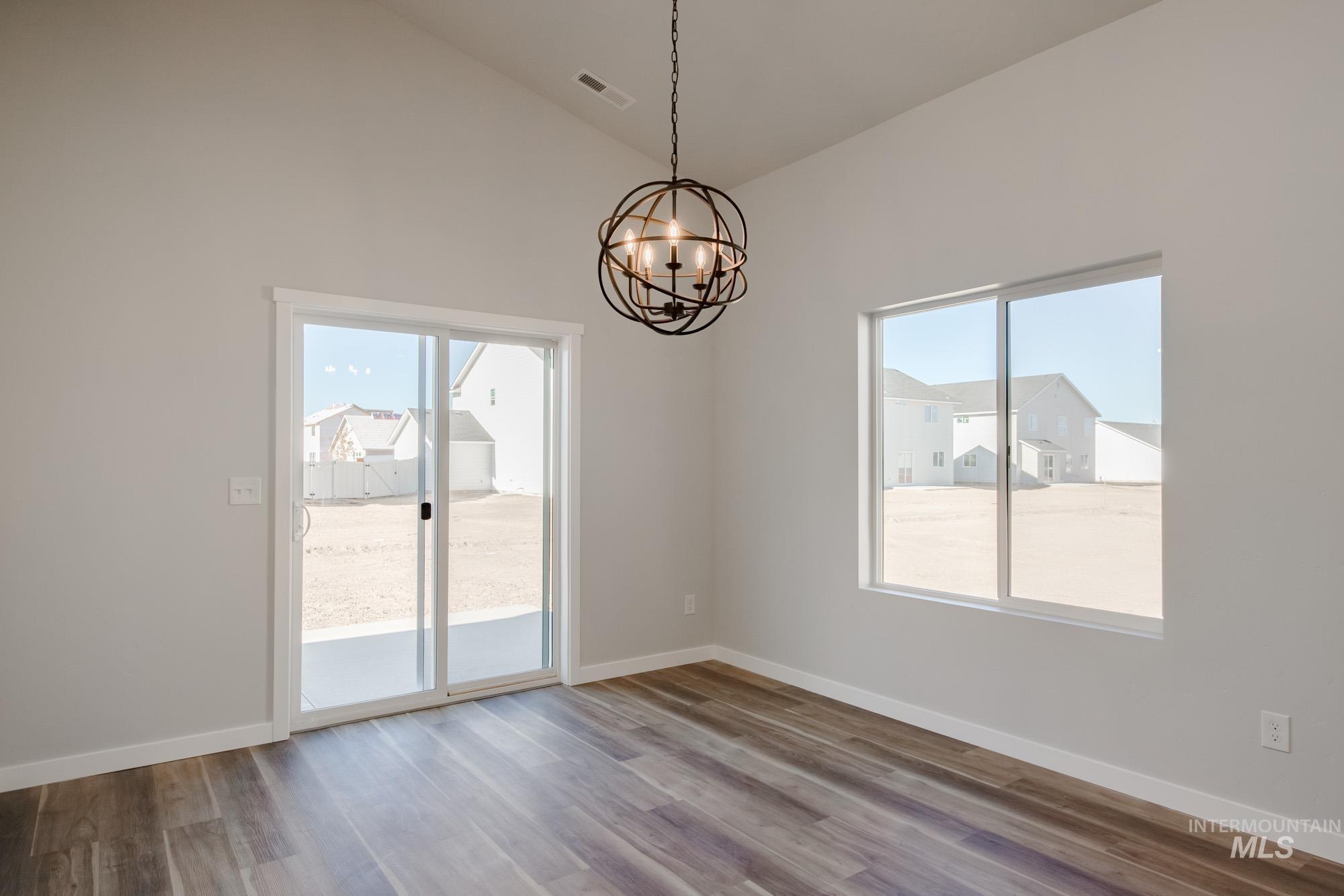13723 Nisene Street Caldwell, ID 83607 - Photo 9 of 22 Unfurnished room with plenty of natural light, a chandelier, wood finished floors, and high vaulted ceiling