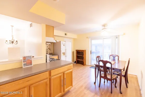 a dining hall with stainless steel appliances kitchen island granite countertop a table chairs and a refrigerator