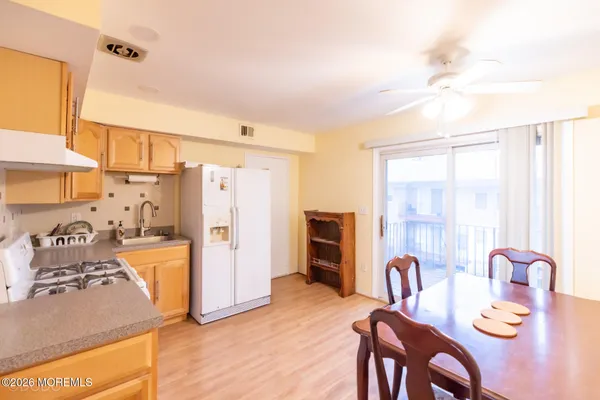 a kitchen with stainless steel appliances kitchen island granite countertop a refrigerator a stove top oven and a dining table with wooden floor