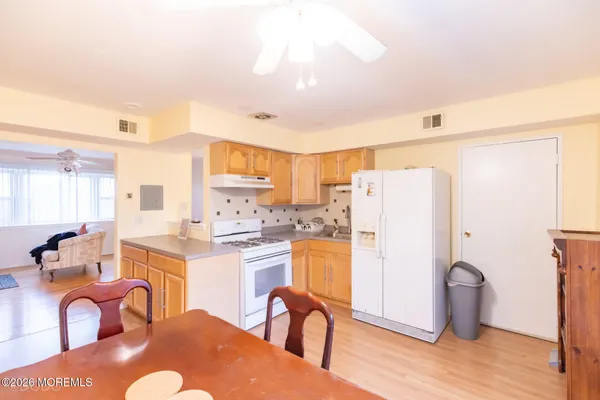 a kitchen with stainless steel appliances granite countertop a refrigerator a stove a sink dishwasher and white cabinets with wooden floor