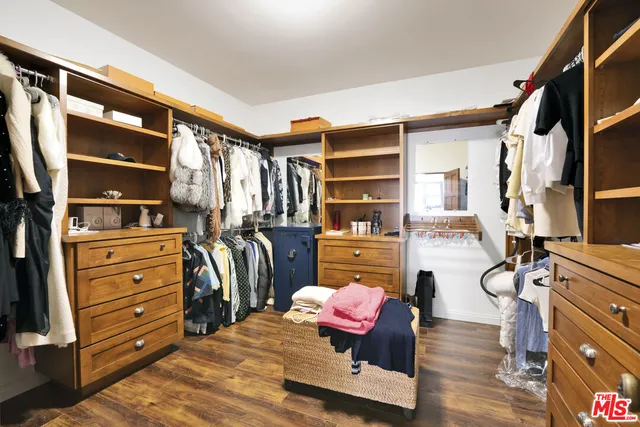 a view of walk in closet with clothes and shoes