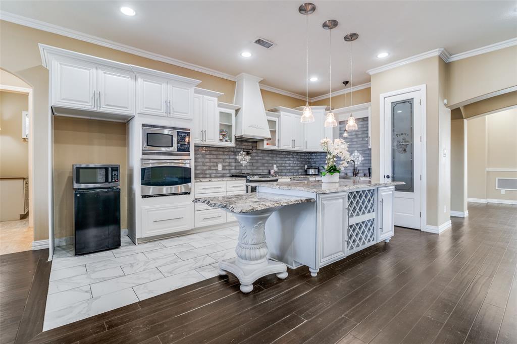 511 East Cook Street, Unit 1 Josephine, TX 75173 - Photo 11 of 29 a kitchen with kitchen island granite countertop a refrigerator a sink a stove and white cabinets with wooden floor