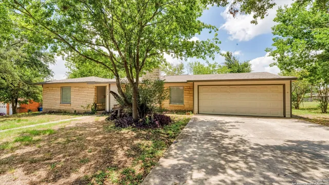 a view of a house with a yard and large tree