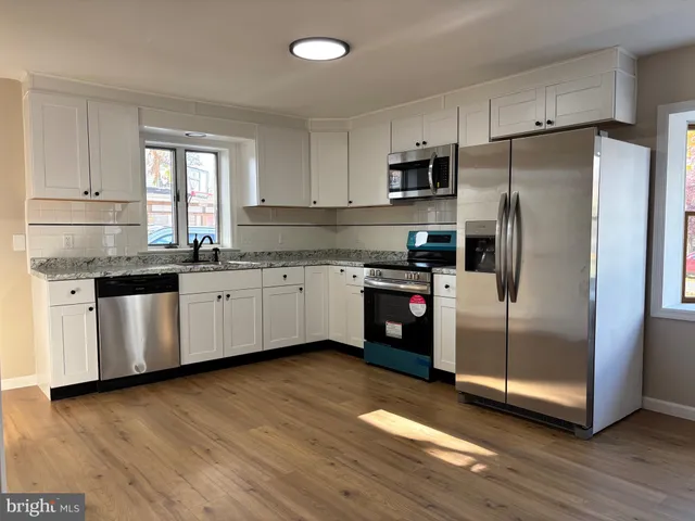 a kitchen with stainless steel appliances a sink cabinets and wooden floor