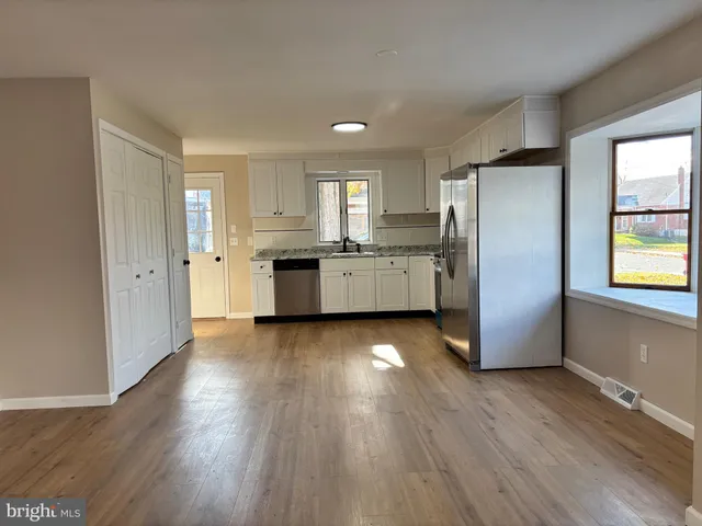 a kitchen with stainless steel appliances granite countertop a refrigerator a sink dishwasher a stove with wooden floors and wooden cabinets