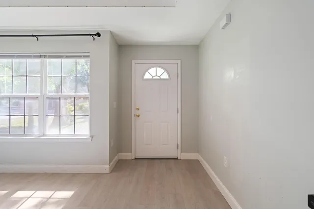 an empty room with wooden floor and windows