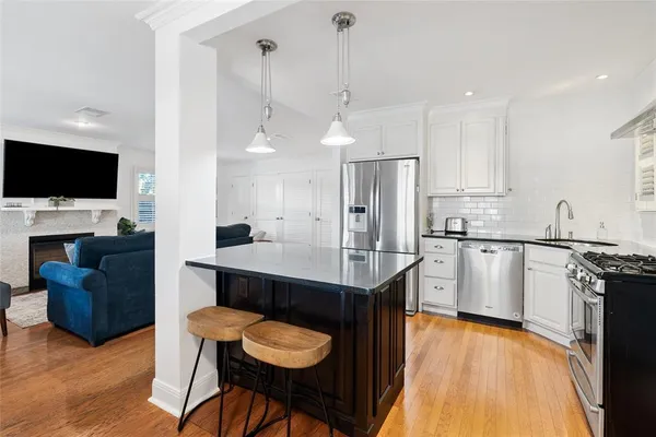 a kitchen with stainless steel appliances granite countertop a stove a sink a microwave a refrigerator and chairs