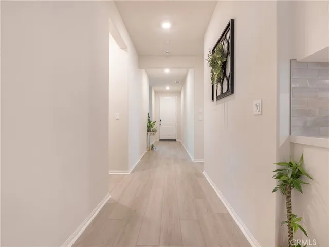 a view of a hallway with wooden floor and a potted plant