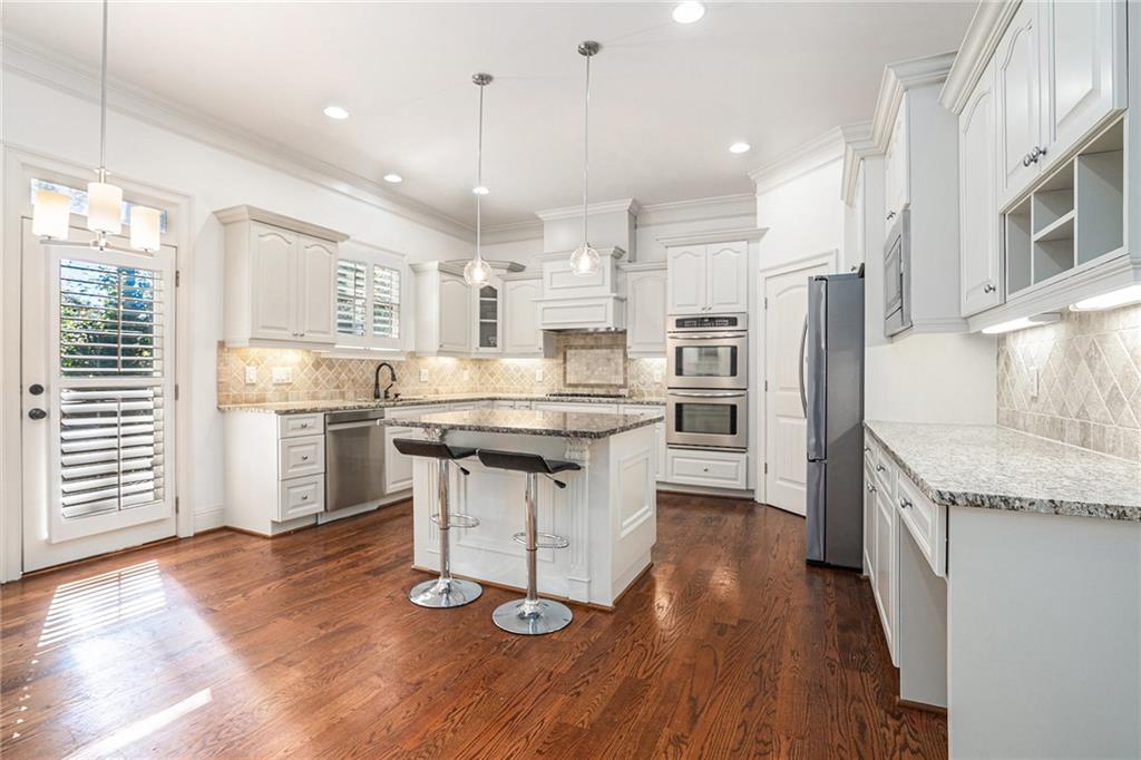 3301 Chastain Ridge Drive Marietta, GA 30066 - Photo 11 of 50 a kitchen with stainless steel appliances kitchen island granite countertop a refrigerator a oven a stove and white cabinets with wooden floor