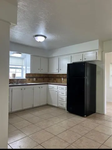 a kitchen with a refrigerator a stove top oven and cabinets