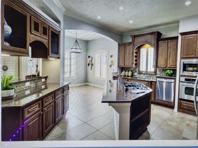 a kitchen with stainless steel appliances granite countertop a sink a stove and a wooden cabinets