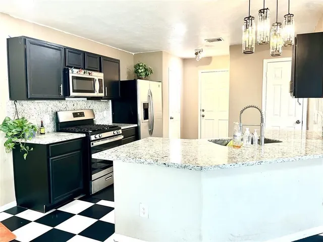 a kitchen with stainless steel appliances kitchen island granite countertop a refrigerator and a sink