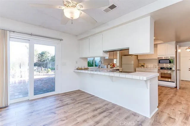 a kitchen with stainless steel appliances granite countertop a stove a sink dishwasher and a refrigerator with wooden floor