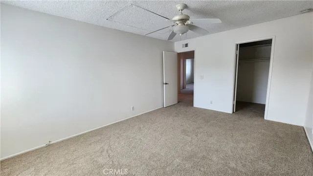 an empty room with windows and a ceiling fan