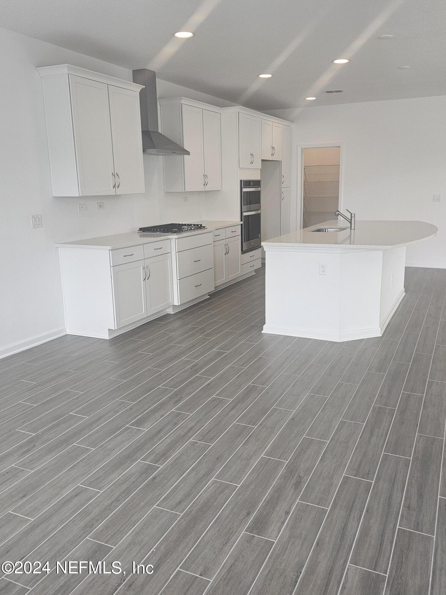 183 Bluegrass Way St. Augustine, FL 32092 - Photo 6 of 9 a large kitchen with stainless steel appliances a sink dishwasher a refrigerator and white cabinets with wooden floor