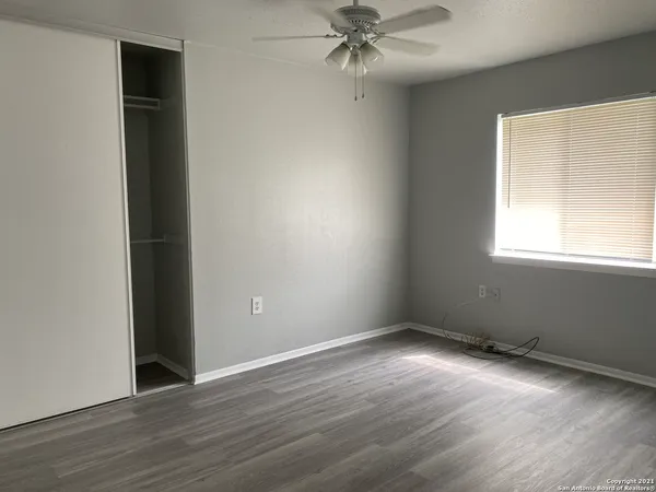an empty room with wooden floor closet and windows