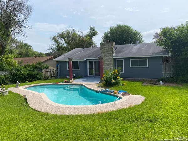 a view of house with swimming pool and yard