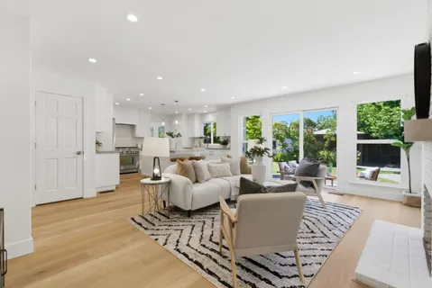 a living room with furniture large windows and wooden floor
