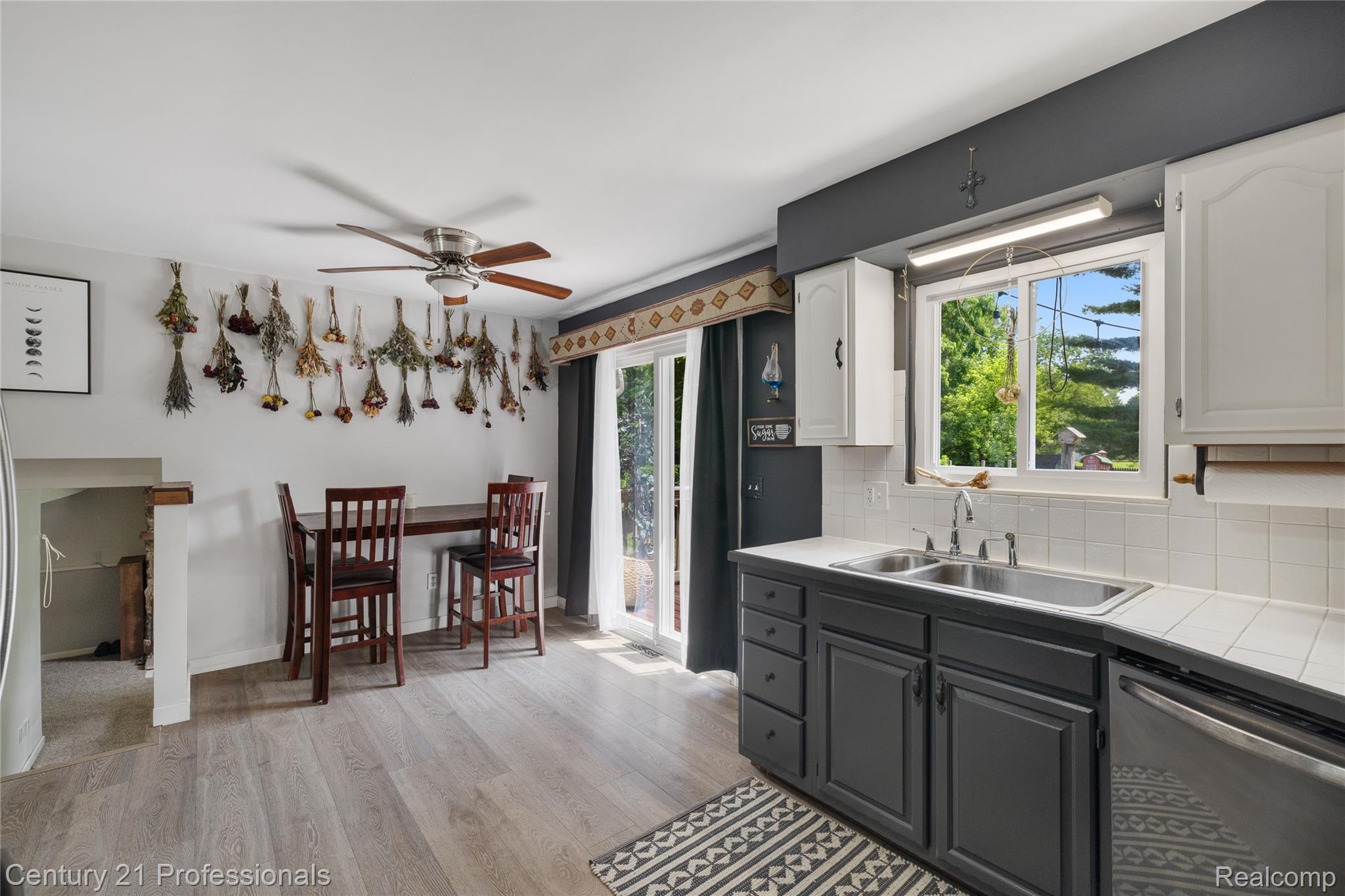 15037 Hogan Road Linden, MI 48451 - Photo 12 of 38 Kitchen featuring light wood-finish flooring, white cabinetry, dark lower cabinetry, and a double basin sink