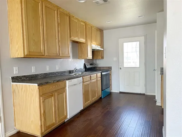 a kitchen with granite countertop wooden floors and white cabinets