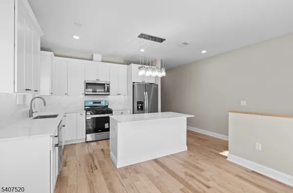 a living room with stainless steel appliances furniture a refrigerator a sink a stove a microwave and cabinets