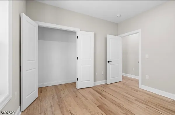 a view of an empty room with wooden floor and closet