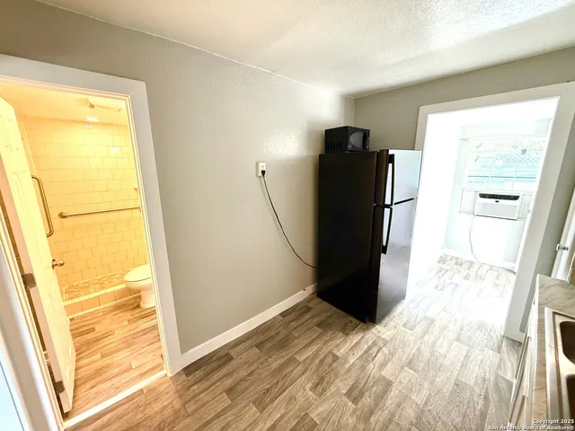 a view of a refrigerator in kitchen and an empty room