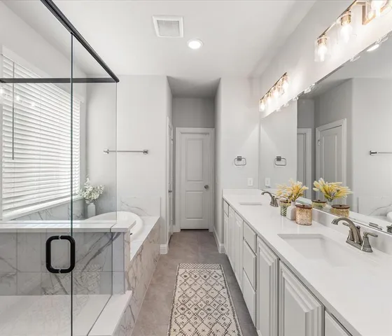 a bathroom with a double vanity sink a mirror and a bathtub