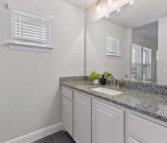 a bathroom with a granite countertop sink and a mirror