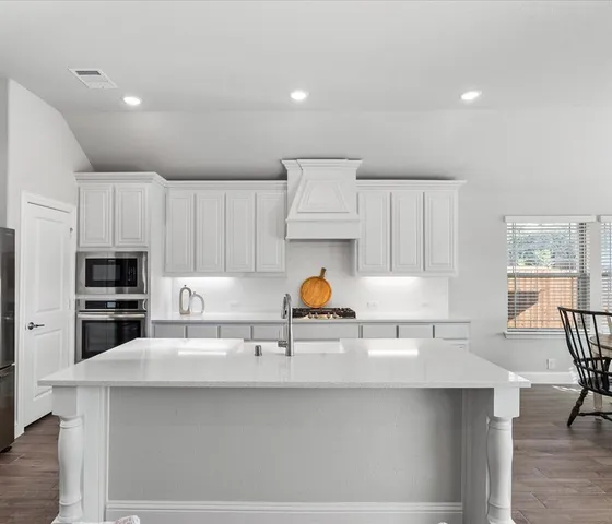 a kitchen with stainless steel appliances a sink a stove a refrigerator and cabinets