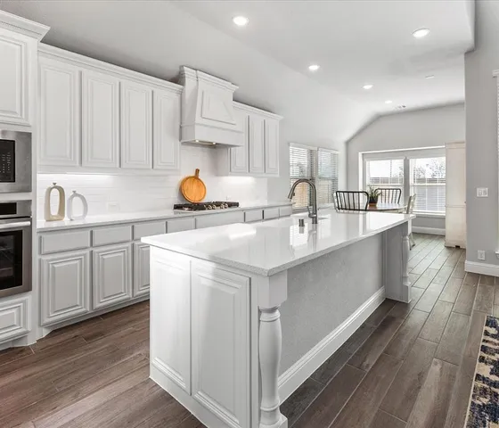 a kitchen with kitchen island granite countertop a sink a counter space appliances and cabinets