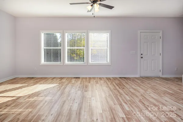a view of an empty room with a window and wooden floor