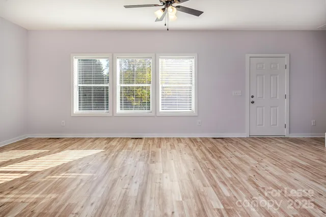 a view of an empty room with a window and wooden floor
