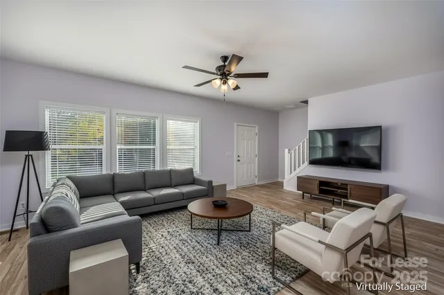 a living room with furniture a flat screen tv and a large window