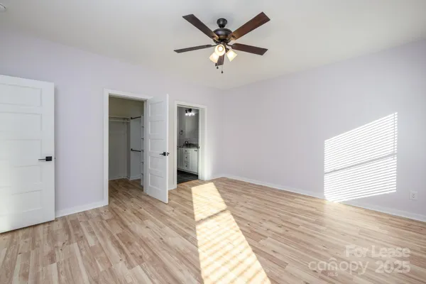 a view of empty room with wooden floor and fan
