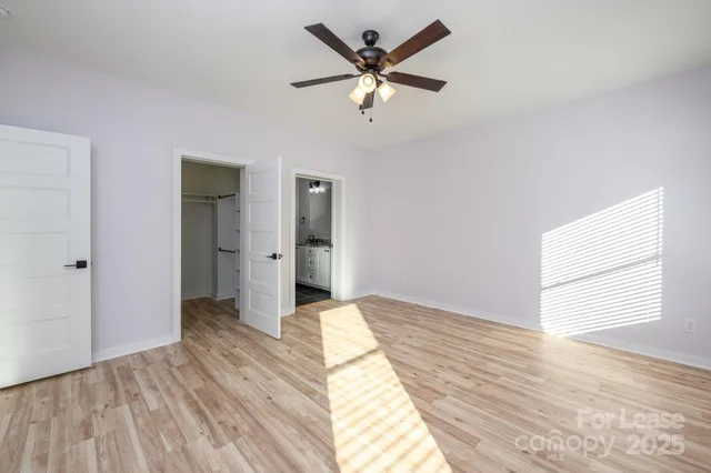 a view of empty room with wooden floor and fan