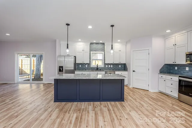 a large kitchen with granite countertop a stove top oven a sink dishwasher and a refrigerator with wooden floor