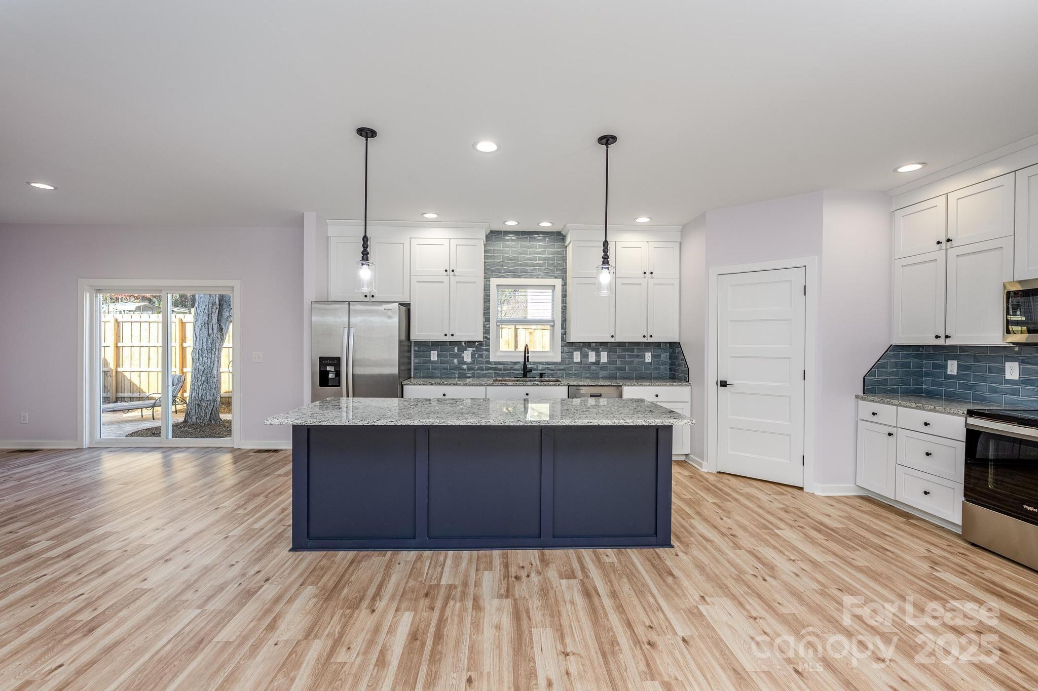 7039 Executive Circle Denver, NC 28037 - Photo 2 of 48 a large kitchen with granite countertop a stove top oven a sink dishwasher and a refrigerator with wooden floor