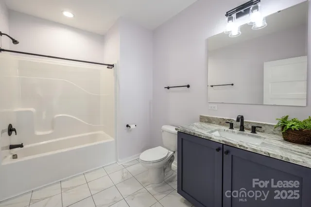 a bathroom with a granite countertop sink a toilet and shower