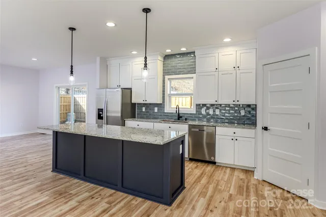 a large kitchen with granite countertop a sink a counter space appliances and cabinets