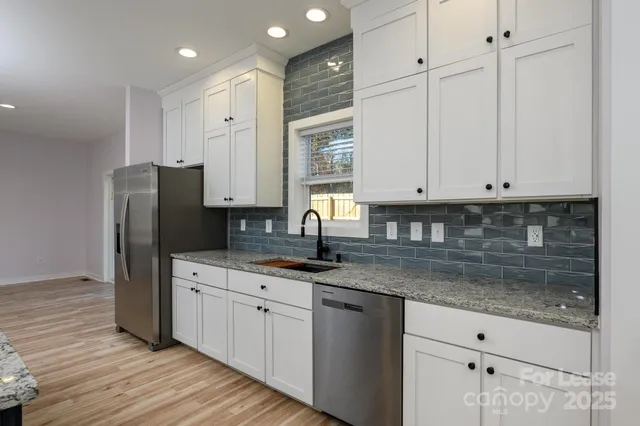 a kitchen with stainless steel appliances granite countertop a sink and a refrigerator