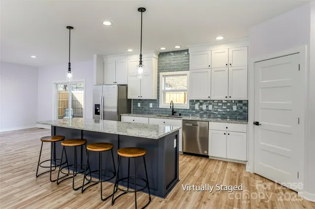a large kitchen with kitchen island granite countertop a table chairs sink and cabinets